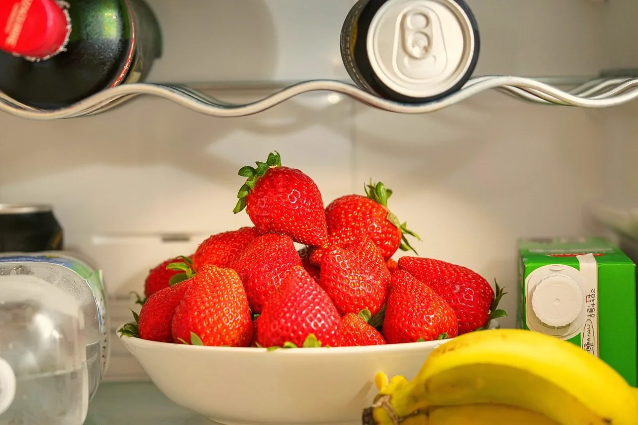 Clear organizer bins with food on a refrigerator shelf